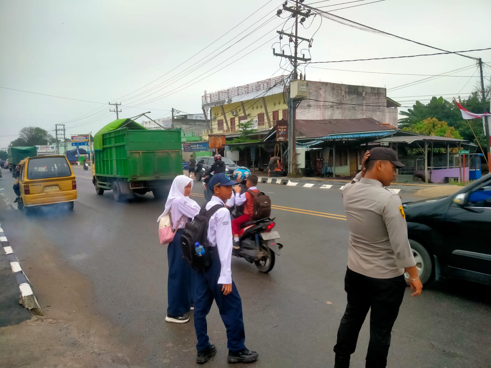 Petugas Seberangkan Siswa Menuju Sekolah,  Saat Lalu Lintas Kendaraan Di Ogan Ilir Ramai